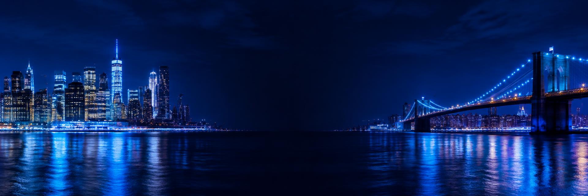 New York waterfront and Brooklyn Bridge lit in blue at night